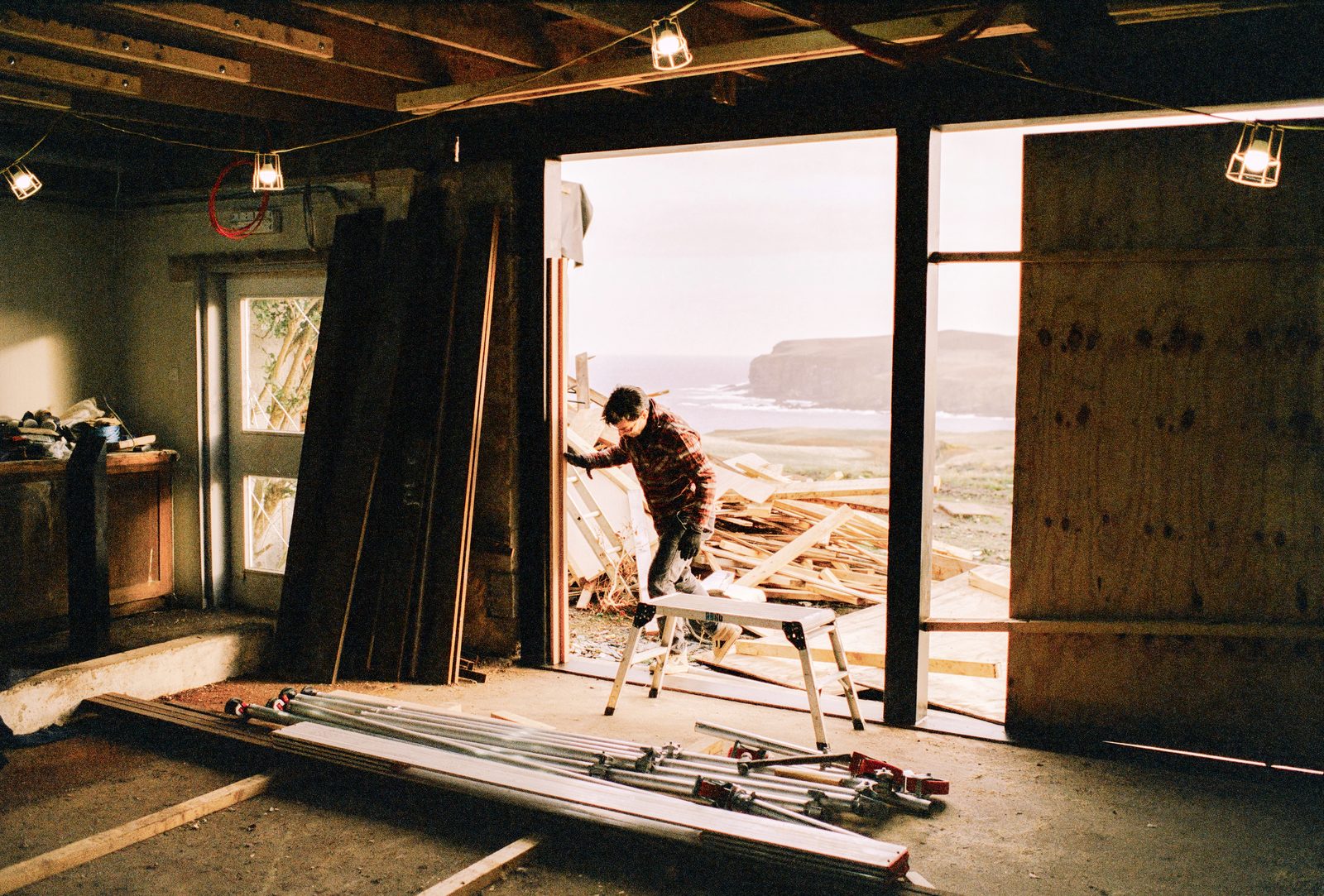 A worker at a tall sea-view doorway during the build