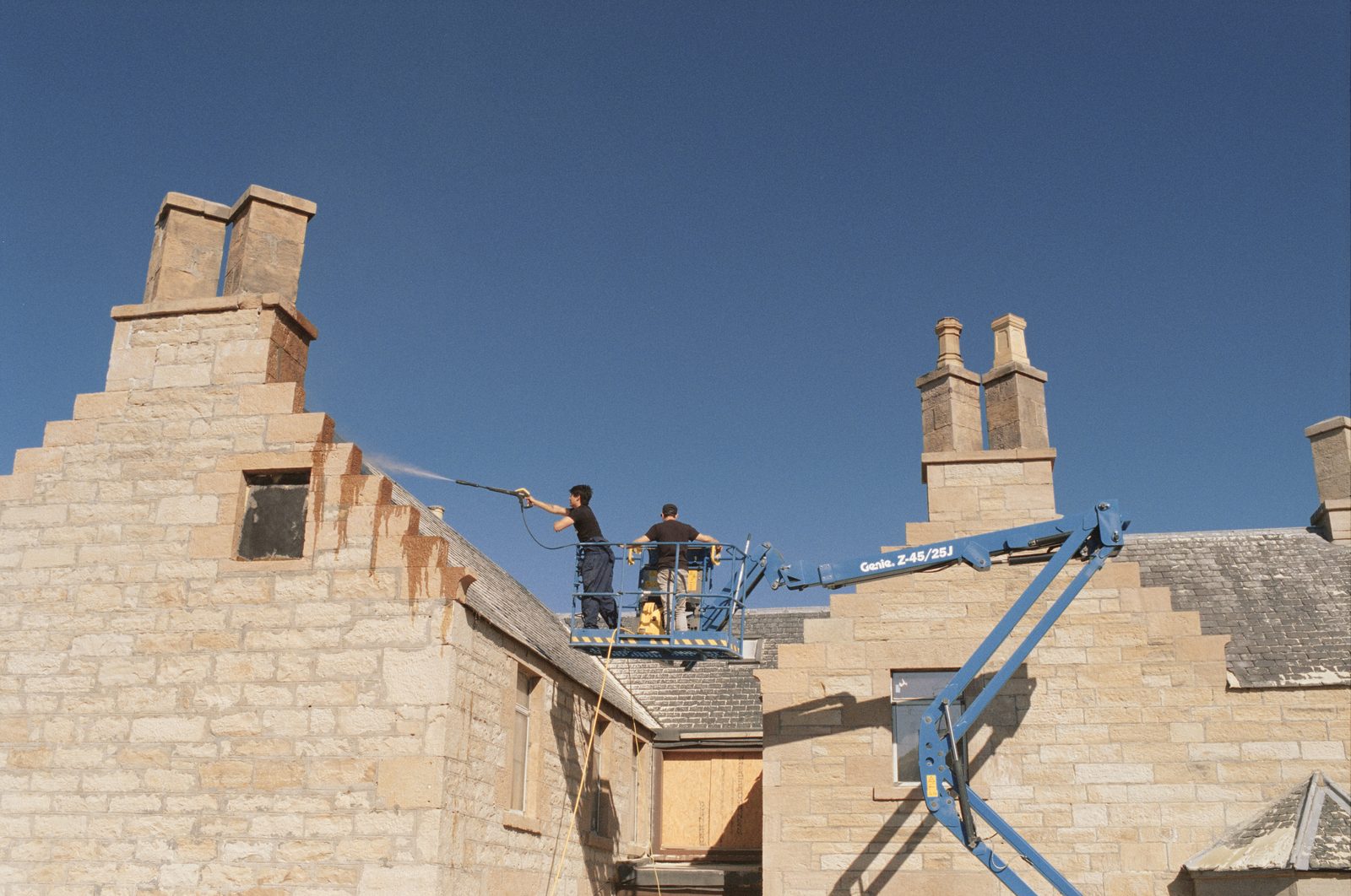 Stonework on the roof with a blue cherry picker